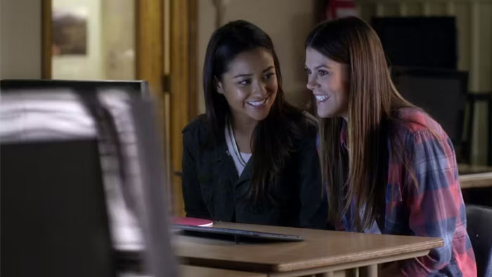 Two women sitting at a desk, smiling at a computer screen, illustrating TV couples with less chemistry.