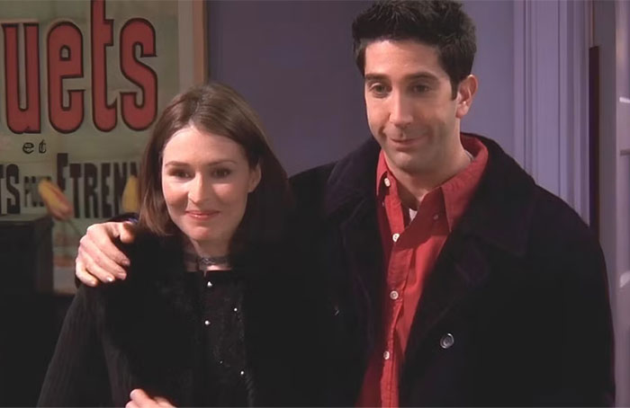 TV couple with less chemistry, standing together awkwardly indoors.