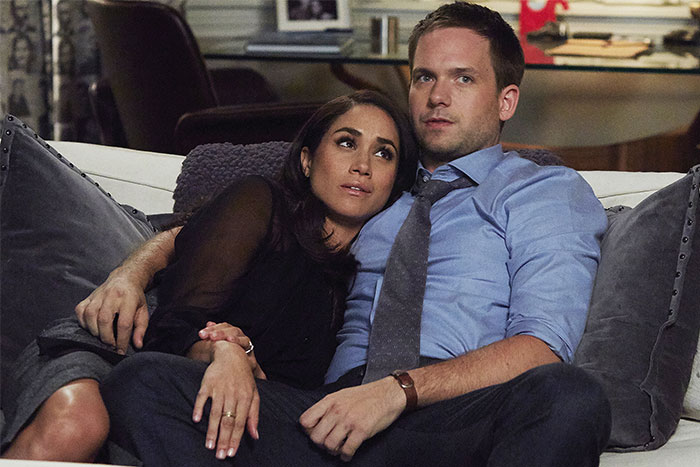 TV couple on a couch lacking chemistry, woman resting her head on man's shoulder.