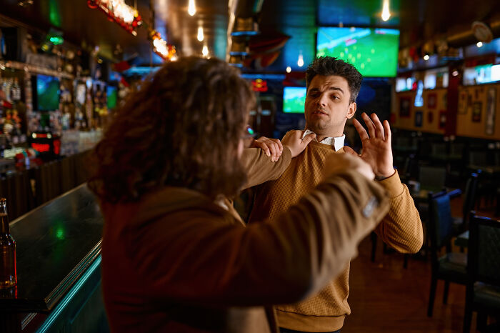Two men in a lively bar, engaged in a playful altercation, embodying a "mess around, find out" moment.