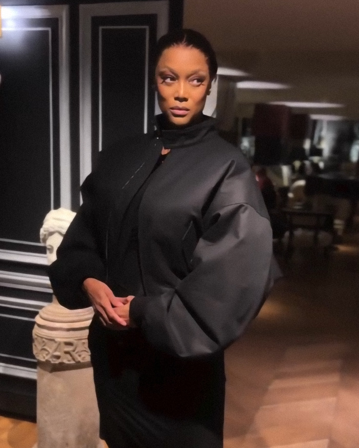 Tyra Banks with taut skin in black jacket at Paris Fashion Week event.