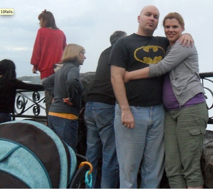 Pareja sonriente en mirador, rodeada de gente, capturando un momento con una historia inquietante oculta.