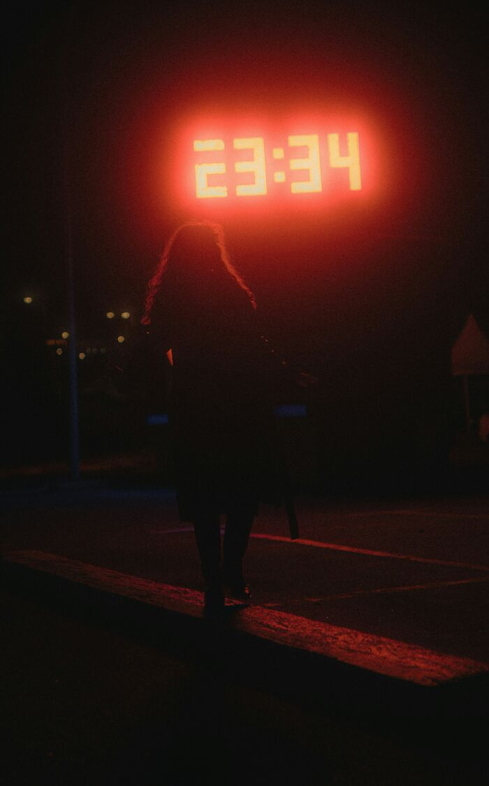 Silhouette of a person near a bright red digital clock displaying 23:34, related to undercover cops' stories.