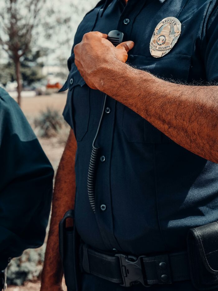Undercover cop holding a radio, uniform details visible, highlighting intense and secretive police work.