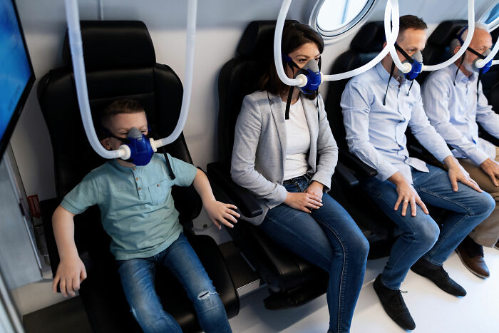 People sitting in a row, wearing breathing masks inside a pressurized cabin, showcasing unexpected things in reality.