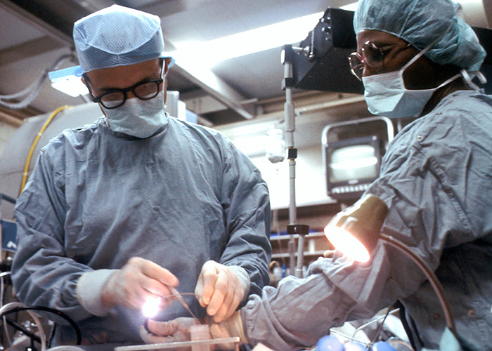 Two surgeons performing surgery in an operating room, focusing on medical procedures in a sterile environment.