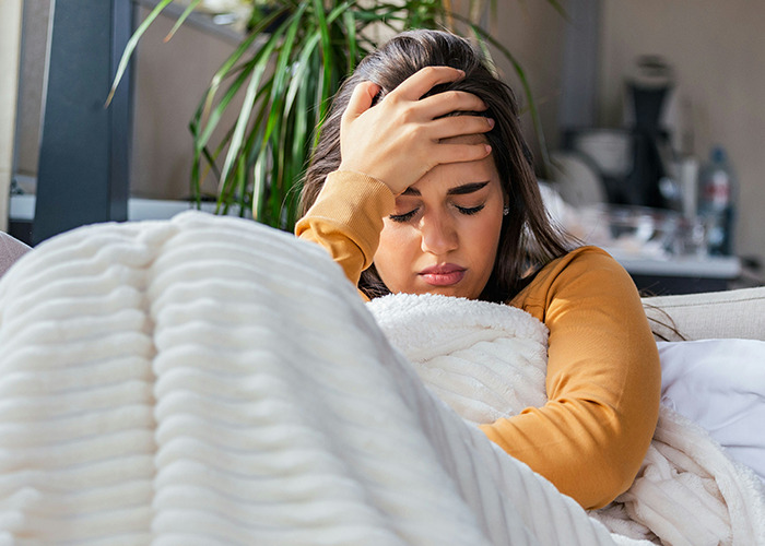 Influencer looking distressed, sitting on a couch covered with a blanket, possibly sharing unsettling facts.