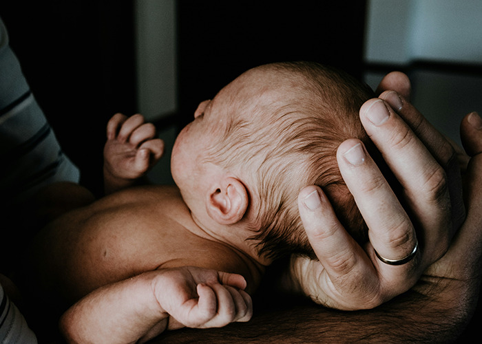 A person gently holding a newborn baby, illustrating a calming and intimate moment.