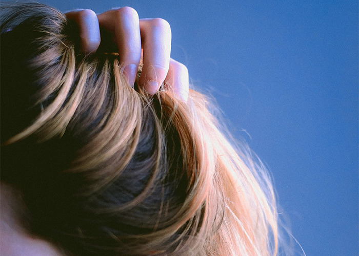 Person grasping their hair against a blue background, related to unusual facts shared by an influencer.