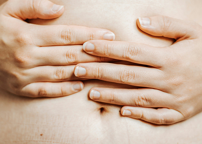 Hands on a stomach, conveying unusual and unsettling facts shared by an influencer.
