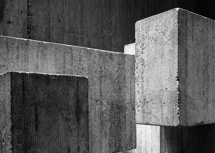 Grayscale image of large, textured concrete blocks creating an unsettling urban landscape.