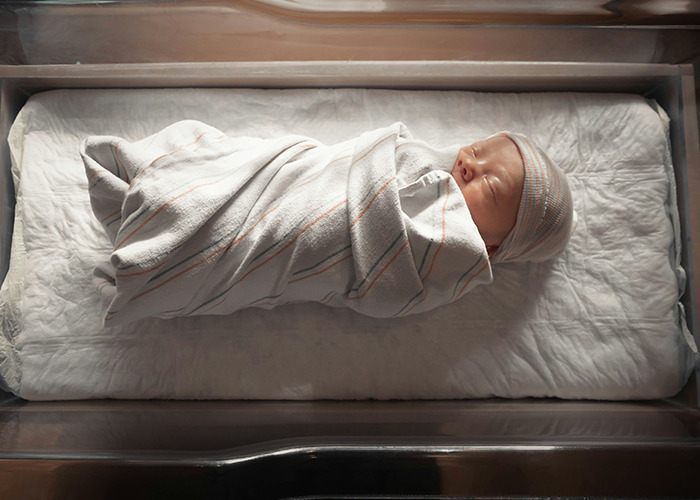 Newborn baby swaddled in a hospital crib, relevant to unusual and unsettling facts shared by an influencer.