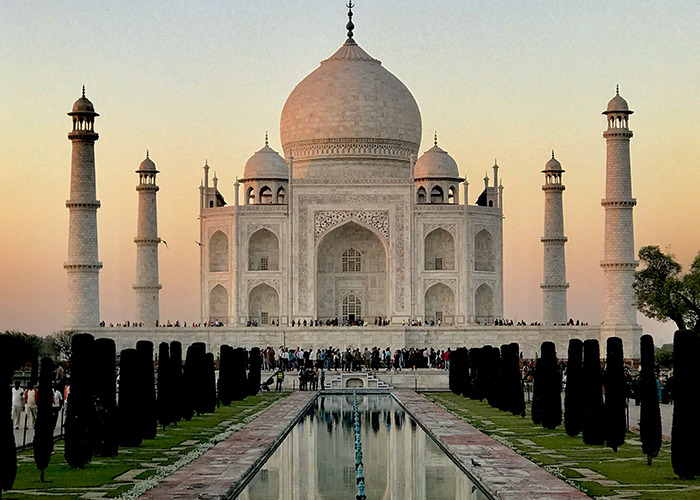 Taj Mahal at sunset with a reflection in the water, highlighting its architectural beauty and historical significance.