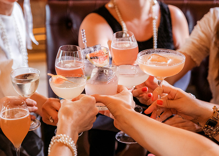 People raising cocktails in a toast, sharing unsettling facts at a social gathering.