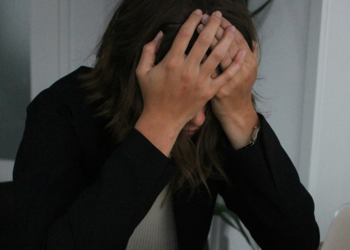 Woman holding her head in distress after hearing unsettling facts from an influencer.