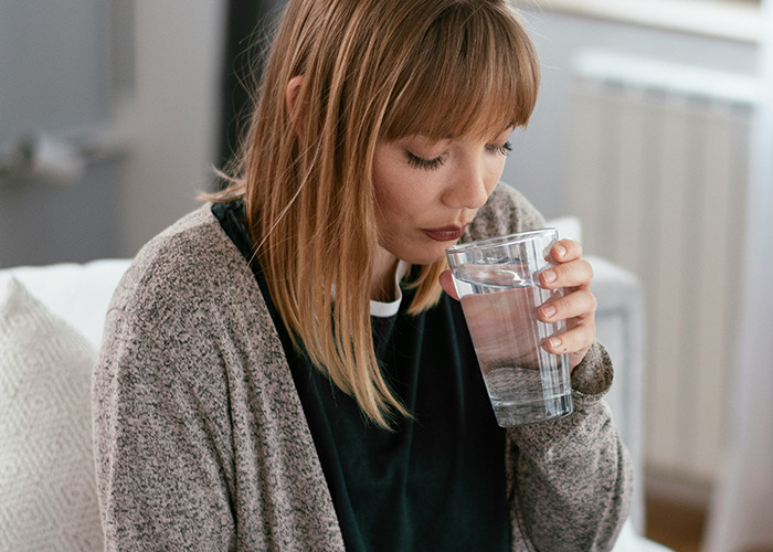Woman drinking water, contemplating unsettling facts shared by an influencer.