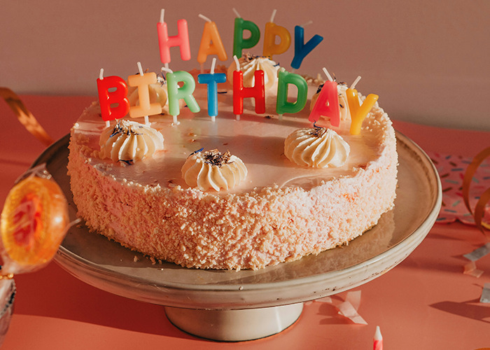 Birthday cake with colorful candles, placed on a pink table, representing unusual and unsettling facts.