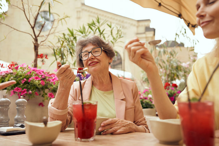 Older woman enjoying dinner with family, sharing a laugh.