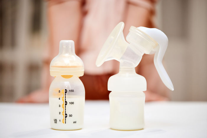 Breast milk in bottles with a breast pump on a table, relevant to a dad microwaving breast milk despite warnings.