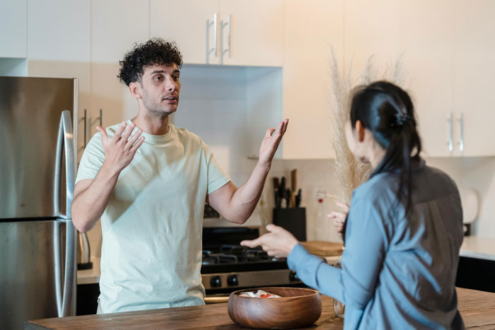 Man and woman in kitchen having a heated discussion about microwaving breast milk for baby.