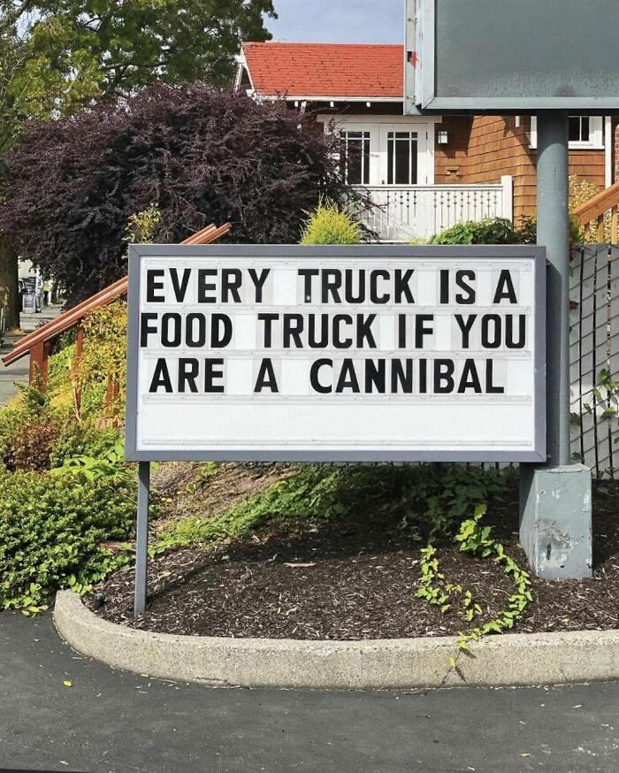 Sign with meme text about every truck being a food truck for cannibals, surrounded by greenery.