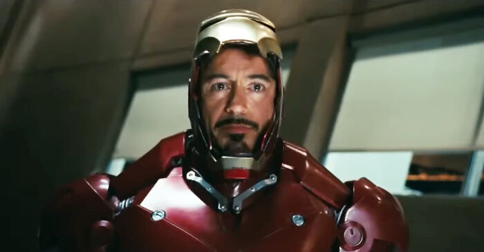 Actor in red and gold armor suit, embodying a role they were born for, staring ahead in a futuristic setting.