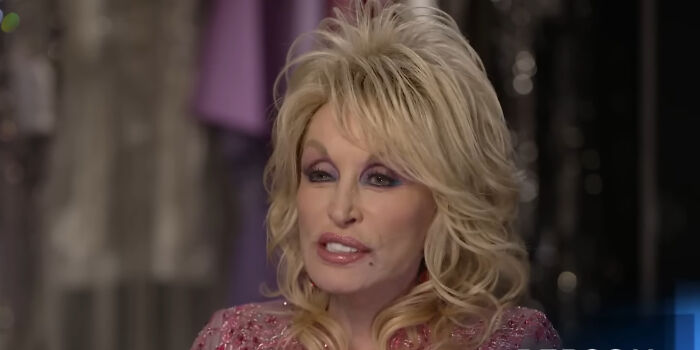 Dolly Parton with blonde hair and pink dress discussing plausible celebrity conspiracy.
