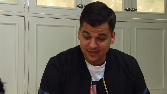 Rob Kardashian in casual attire sitting indoors, engaging in a conversation related to celebrity conspiracy.