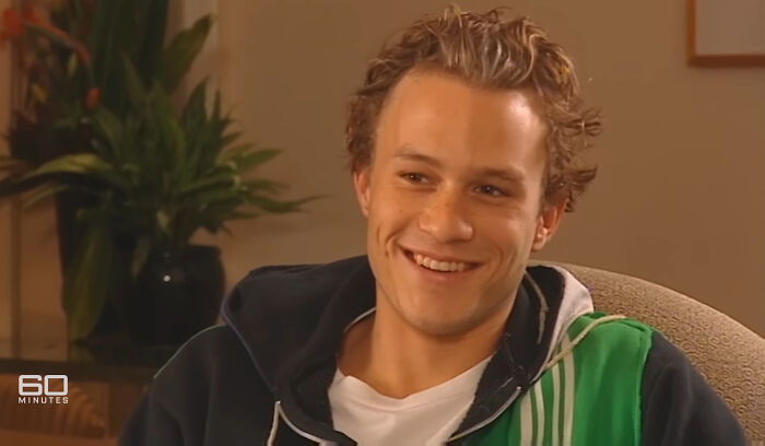 Smiling celebrity during an interview, wearing a casual jacket, engaging in conversation indoors.