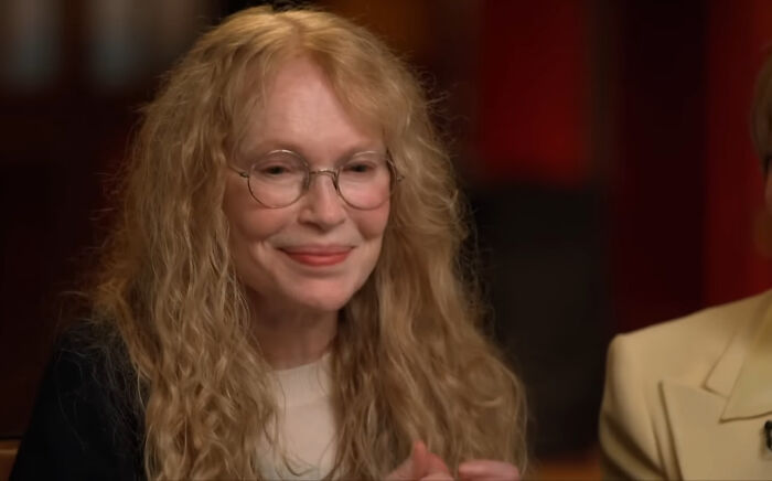 A woman with glasses and long curly hair, related to celebrity conspiracy discussions.