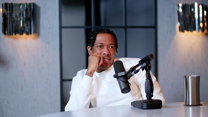 Person in white sweater with microphone, discussing a totally plausible celebrity conspiracy theory in a modern studio.