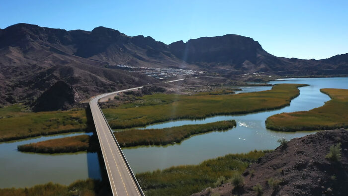 A scenic, serene landscape view with a bridge over a river, surrounded by mountains, less hyped by seasoned travelers.