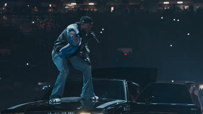 Performer standing on a car during a dramatic concert, capturing a moment rich with wild theories atmosphere.