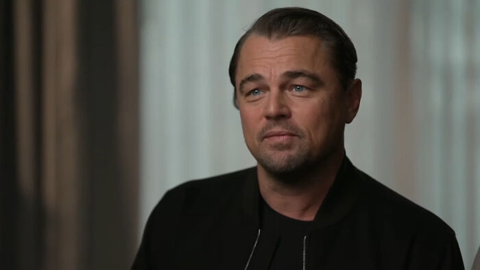 Leonardo DiCaprio in a dark jacket, indoors, associated with a celebrity conspiracy discussion.
