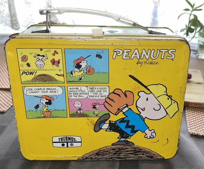 Vintage Peanuts lunchbox featuring Charlie Brown playing baseball, depicting scenes from the classic comic strip.