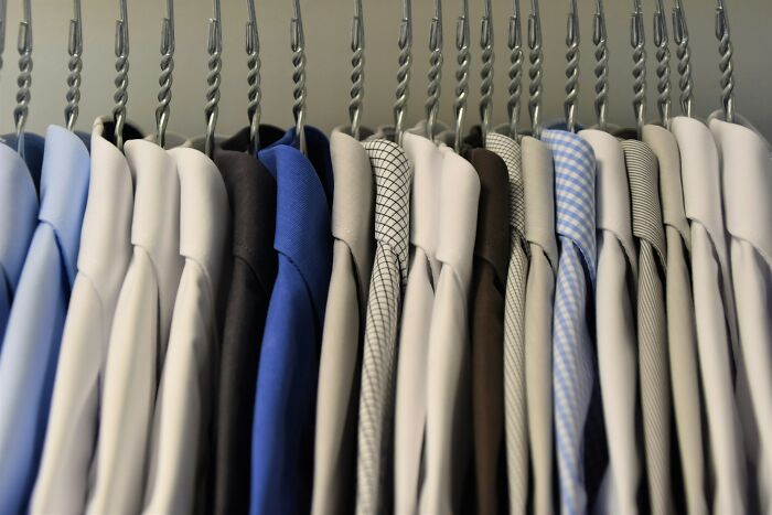 Shirts on hangers in a closet, showcasing a variety of colors and patterns.