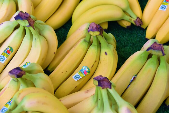Bunches of ripe bananas with small stickers on display, highlighting the concept of innovation in everyday items.