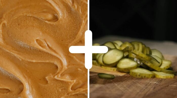 Weird food combo of peanut butter and sliced pickles on a wooden board.