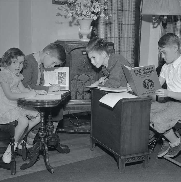 Children studying around a vintage radio, showcasing everyday American life in the past.