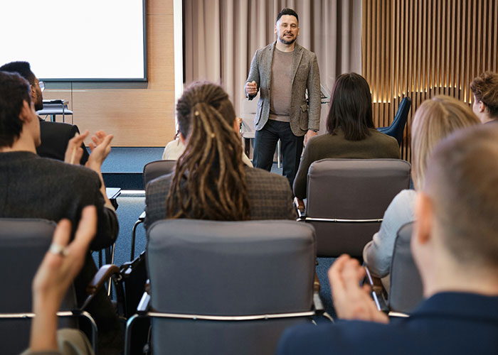 Speaker presenting to an audience in a seminar room, engaging with people about education and kids' future paths.