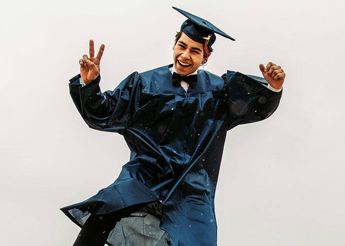 Young graduate in cap and gown celebrating success.