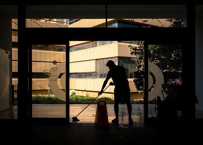 A person mopping a modern building's lobby, highlighting the journey of bright kids and their varied career paths.