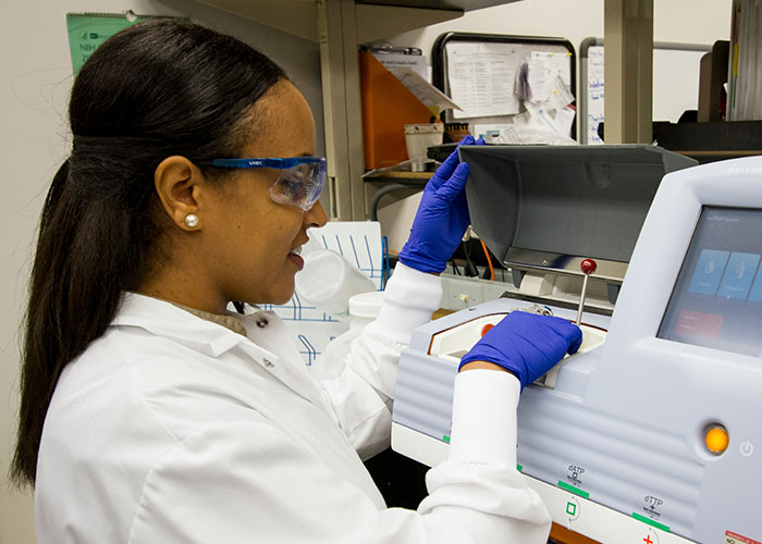 Scientist working in a lab with protective eyewear and gloves, demonstrating where brightest kids from school might end up.