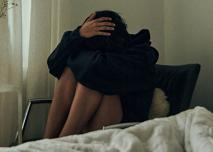 Person sitting in a chair, wearing a dark hoodie, with hands over head, symbolizing where the brightest kids ended up.