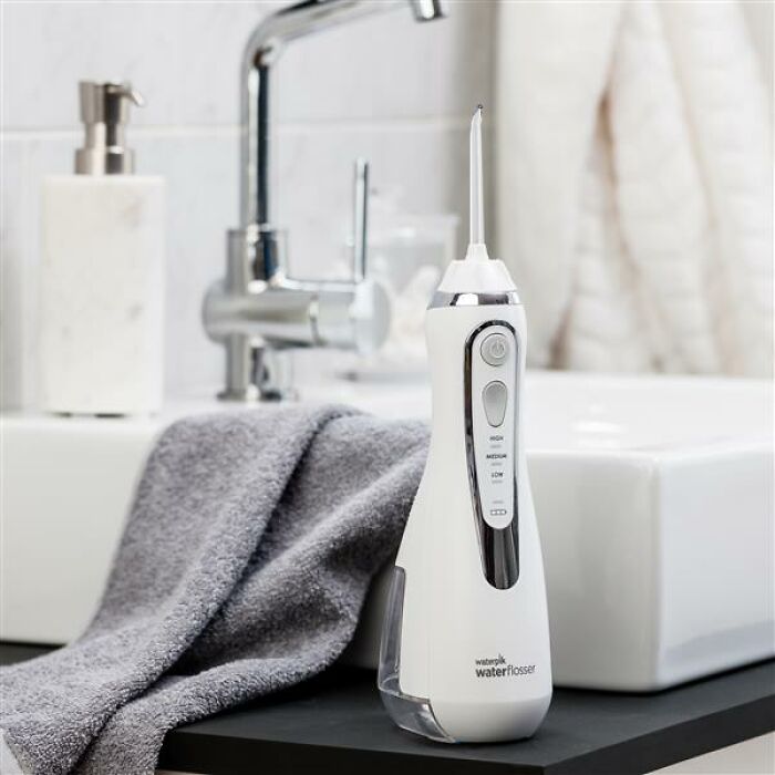 Water flosser next to a towel on a bathroom counter, showcasing impactful items under $500.