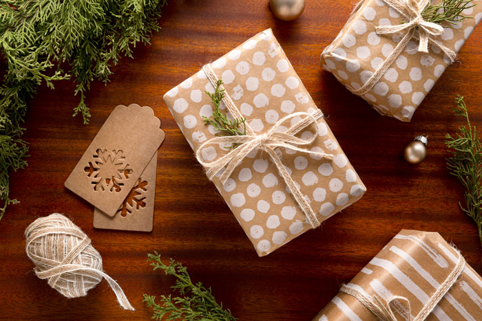 Gift exchange drama: wrapped presents on a wooden table with greenery, highlighting festive atmosphere.