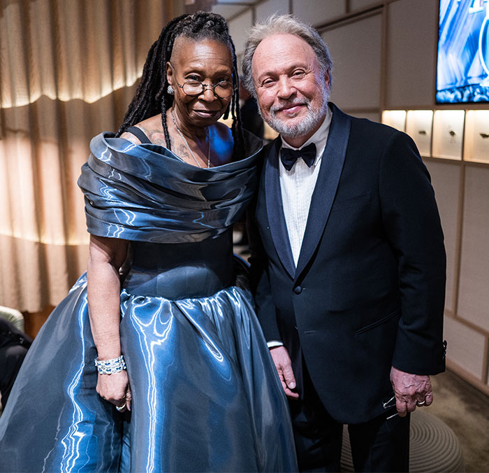 Two people pose together in elegant attire at the Oscars 2025, capturing a behind-the-scenes moment.