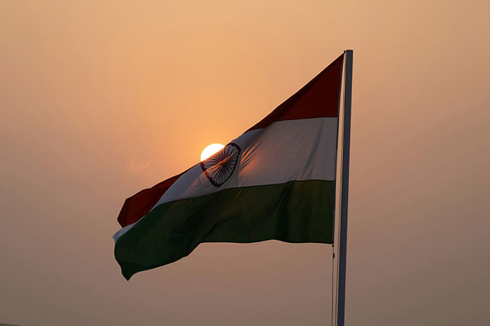 Indian flag waving at sunset, symbolizing relocation to India against a serene backdrop.