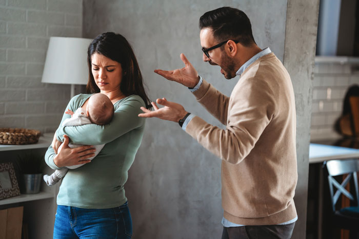 Man arguing with wife holding baby, questioning hygiene. Man arguing with wife holding baby, questioning hygiene.
