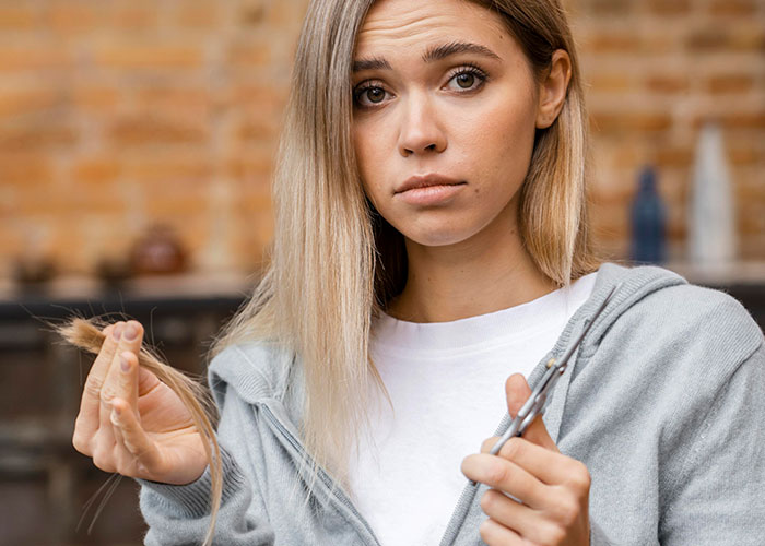 Woman holding scissors and hair, showcasing a wild audition moment with a concerned expression.
